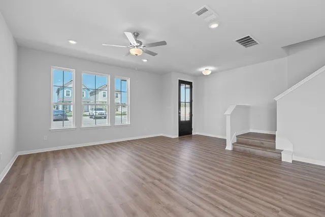 a view of an empty room with a window and wooden floor