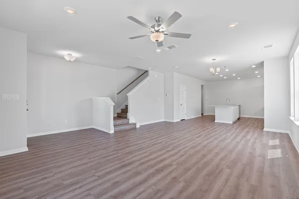 a view of an empty room with wooden floor and a ceiling fan