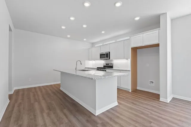 a kitchen with stainless steel appliances a sink stove and wooden floor