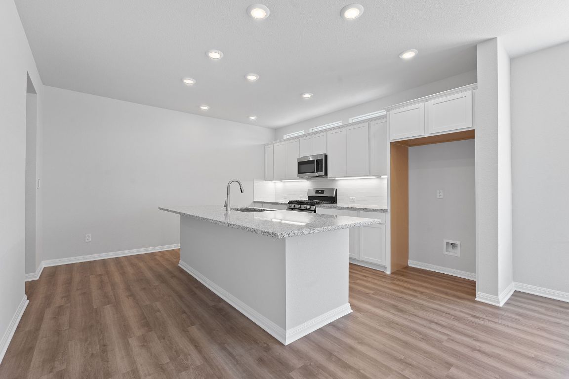 376 Blue Oasis Lane Leander, TX 78641 - Photo 9 of 27 a kitchen with stainless steel appliances a sink stove and wooden floor