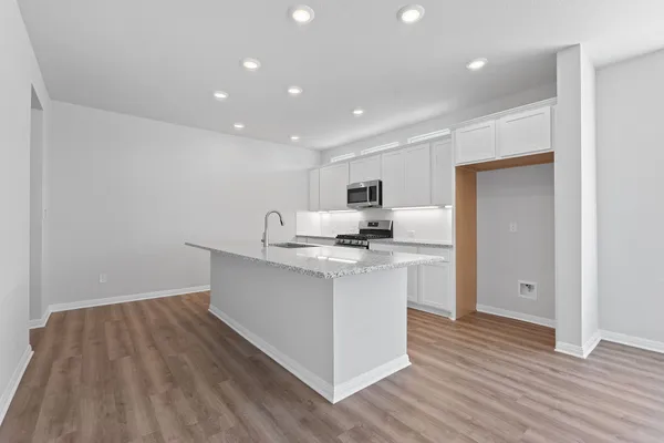 a kitchen with stainless steel appliances a sink stove and wooden floor