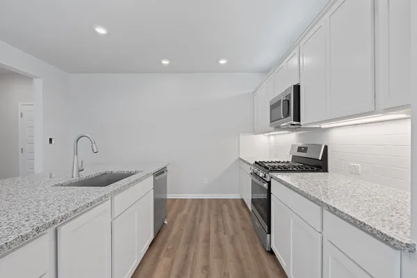 a kitchen with granite countertop a sink stainless steel appliances and white cabinets