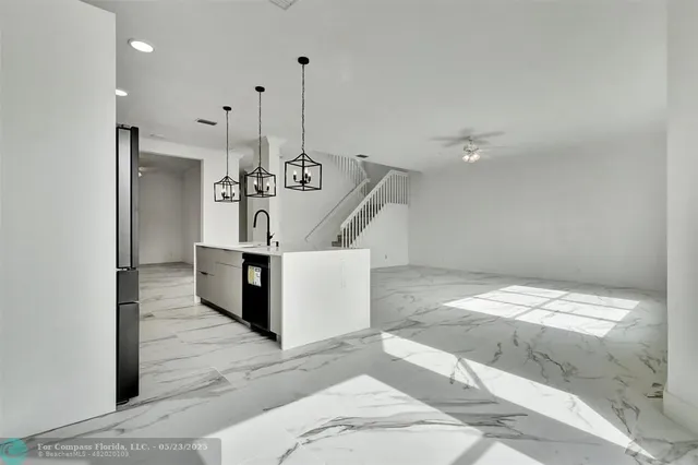 an empty room with wooden floor chandelier fan and windows