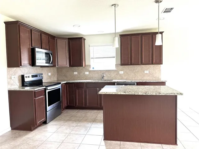 a kitchen with stainless steel appliances granite countertop a stove a sink and a microwave