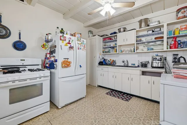 a white kitchen with stainless steel appliances granite countertop a lot of cabinets a washer and dryer