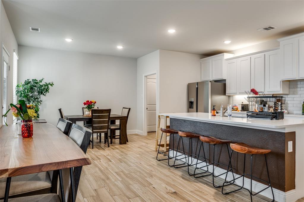 8413 Alba Lane Rowlett, TX 75089 - Photo 8 of 25 Kitchen featuring a kitchen breakfast bar, backsplash, recessed lighting, white cabinets, and stainless steel refrigerator with ice dispenser