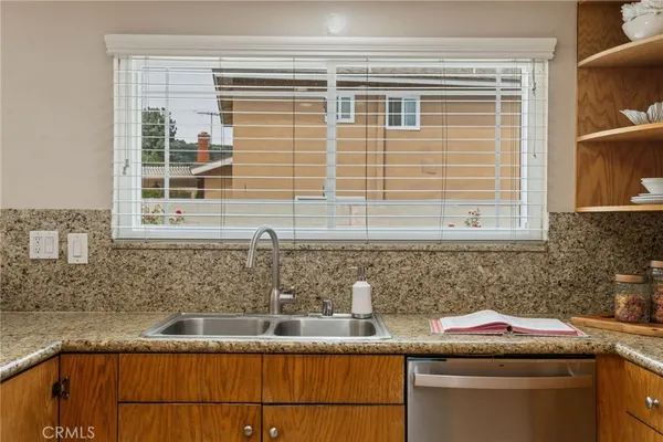 a kitchen with granite countertop sink window and cabinets