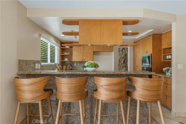 a dining hall with stainless steel appliances granite countertop a table and chairs in it