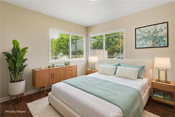 a bedroom with a large bed a potted plant and a window
