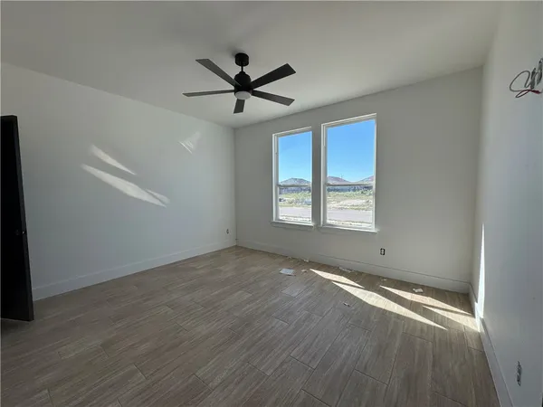 an empty room with wooden floor fan and windows