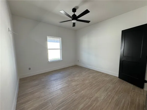 an empty room with wooden floor a ceiling fan and windows