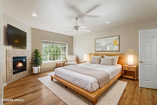 a bedroom with a large bed a flat tv screen and a fireplace