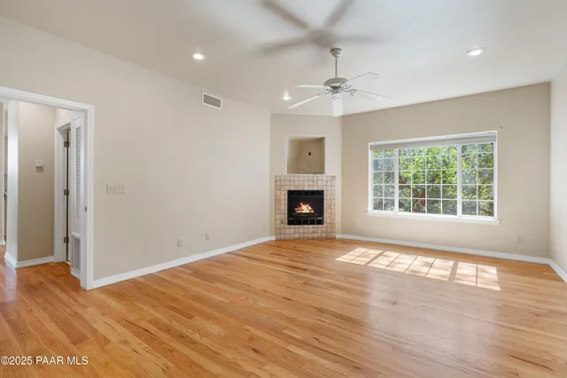 a view of empty room with wooden floor and fan