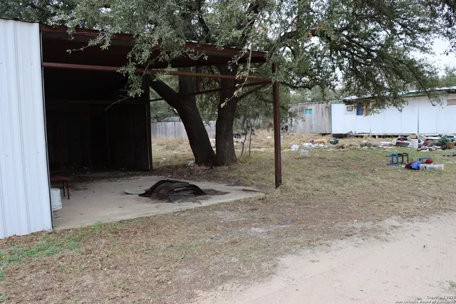 a backyard of a house with barbeque oven and a tree
