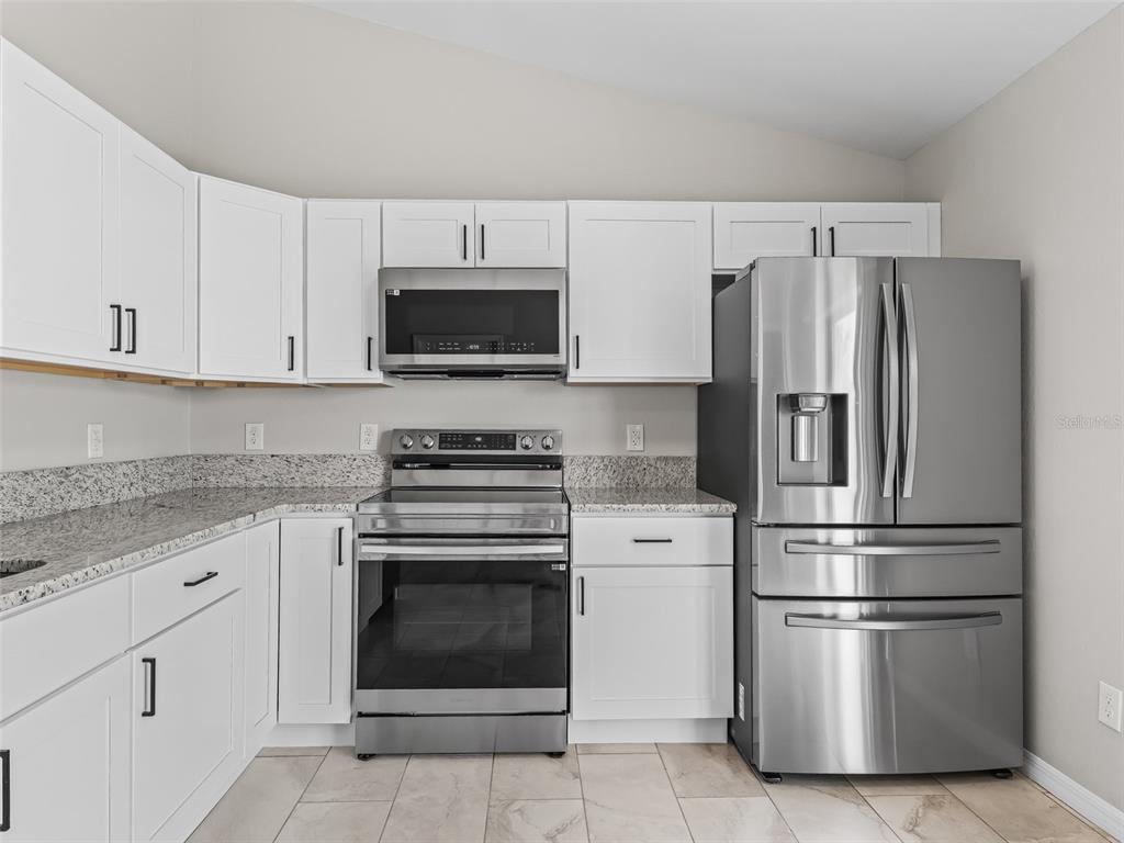 27 Juniper Loop Terrace Ocala, FL 34480 - Photo 13 of 35 a kitchen with stainless steel appliances white cabinets white stove a microwave and a refrigerator