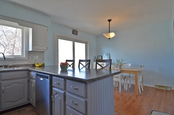 a kitchen with stainless steel appliances granite countertop a sink a stove a refrigerator cabinets and chairs