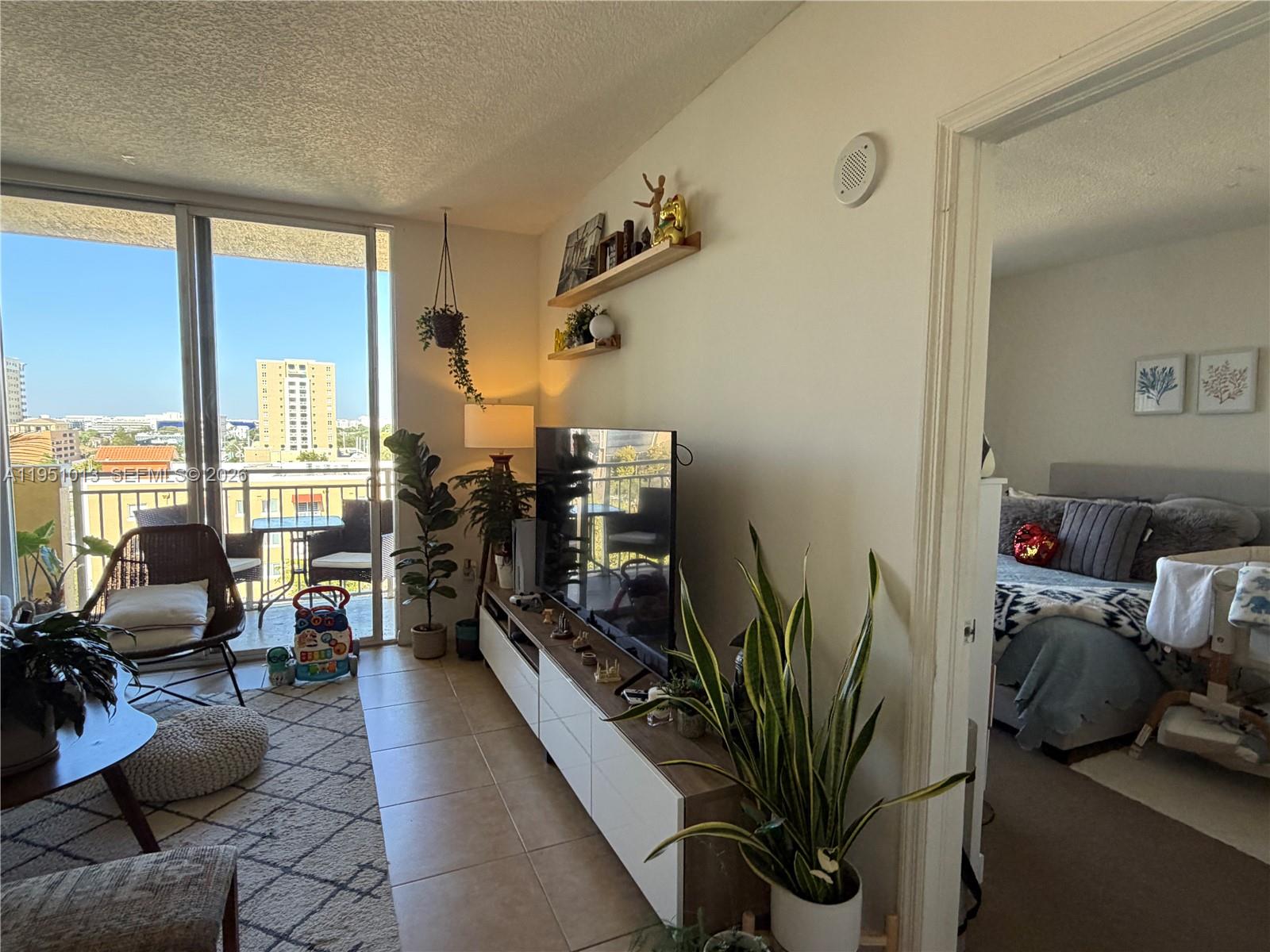 215 Southwest 42nd Avenue, Unit 803 Miami, FL 33134 - Photo 6 of 20 a living room with furniture floor to ceiling window and a flat screen tv