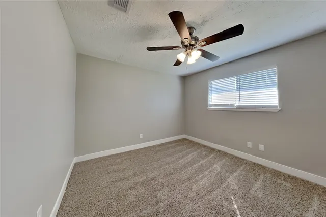 an empty room with a window and a fan