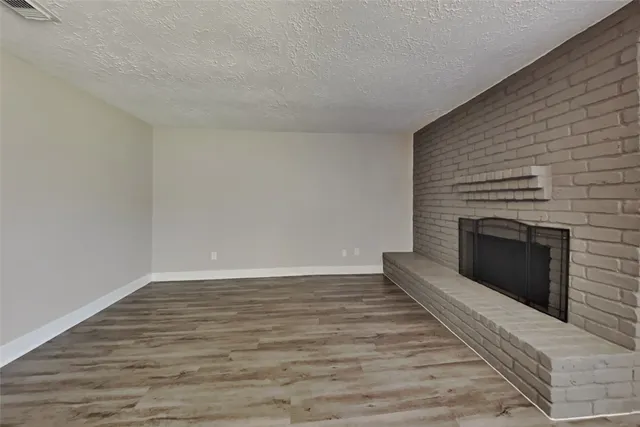 a view of an empty room with wooden floor and fireplace