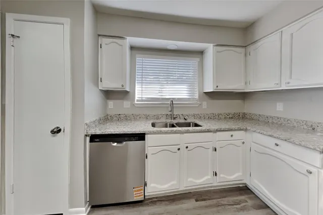 a kitchen with granite countertop white cabinets and a sink