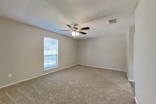 an empty room with windows and ceiling fan