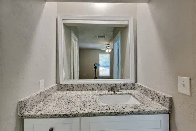 a bathroom with a granite countertop sink and a mirror