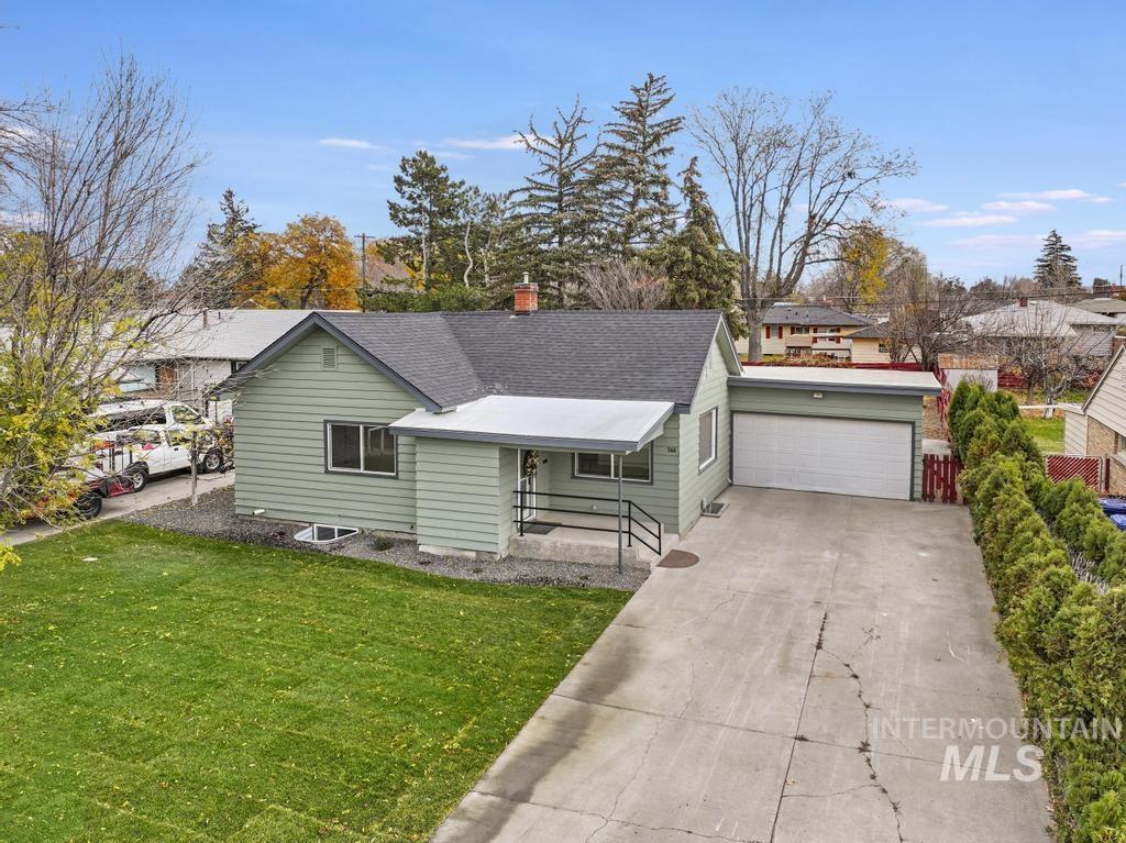 344 Fillmore Street Twin Falls, ID 83301 - Photo 1 of 1 View of front of house featuring driveway, a front yard, a chimney, roof with shingles, and an attached garage