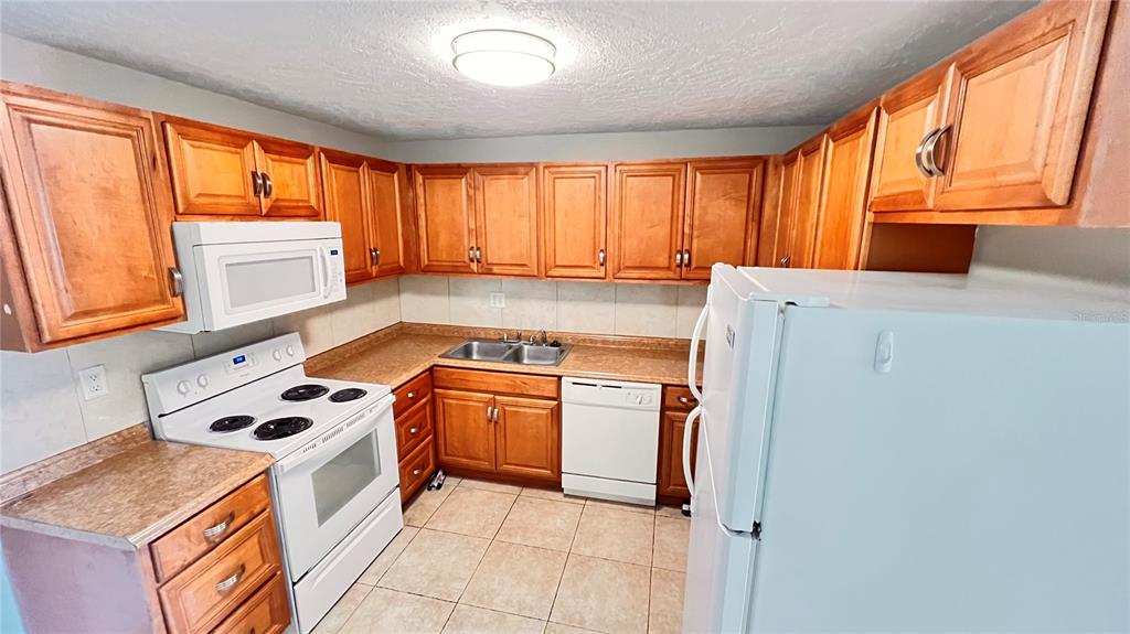 1902 Honour Road, Unit 24 Orlando, FL 32839 - Photo 6 of 25 a kitchen with a stove a sink and a refrigerator