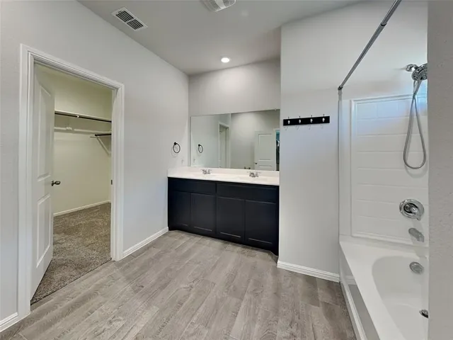 a bathroom with a tub shower vanity and a sink
