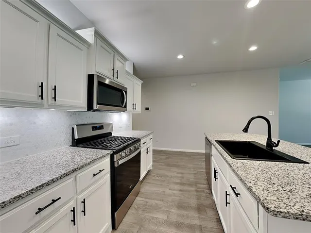 a kitchen with granite countertop a sink and stove top oven