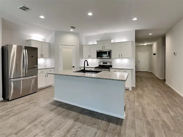 a kitchen with kitchen island a counter top space cabinets and stainless steel appliances