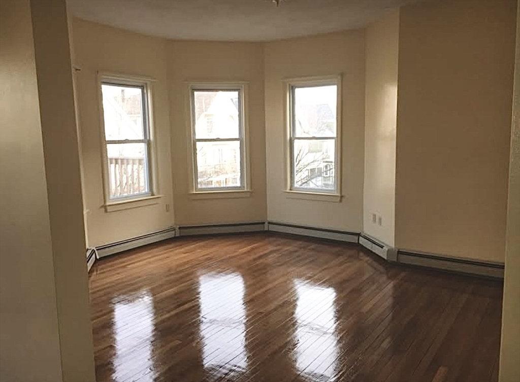 15 Harlem Street, Unit 3 Boston, MA 02121 - Photo 4 of 14 an empty room with wooden floor and windows