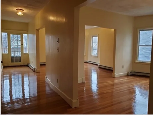 a view of a hallway with wooden floor and windows