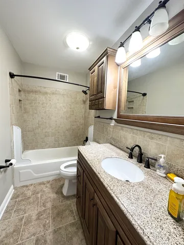 a bathroom with a granite countertop sink a toilet a mirror and bathtub