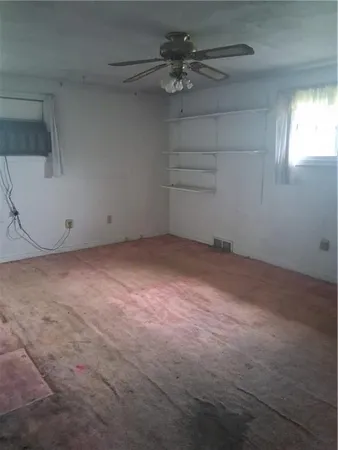 en empty room with windows and fan