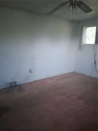 an empty room with a ceiling fan and window
