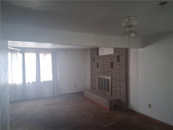 an empty room with windows and fireplace