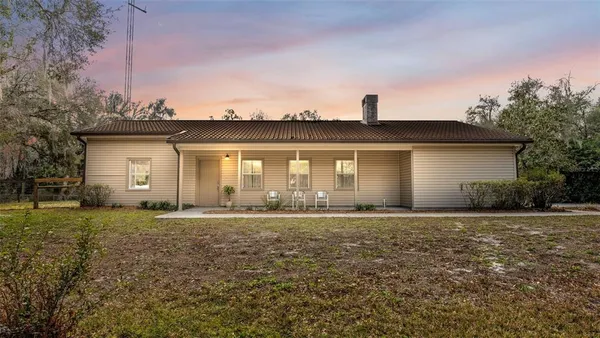 a front view of house with yard and trees in the background