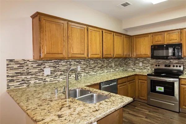 a kitchen with granite countertop a sink stainless steel appliances and cabinets