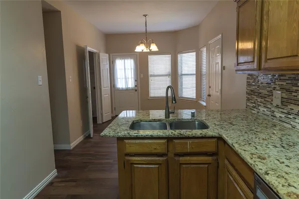 a kitchen with kitchen island granite countertop a counter space windows and a chandelier