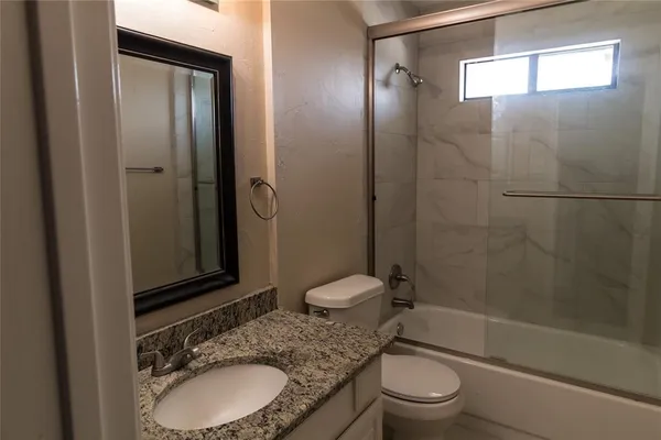 a bathroom with a granite countertop toilet sink and shower