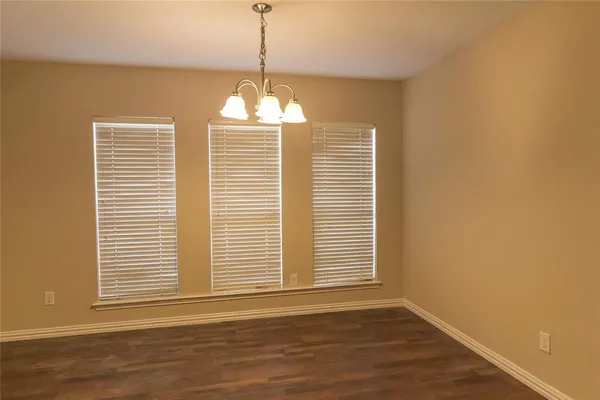 a view of a livingroom with a chandelier wooden floor and windows