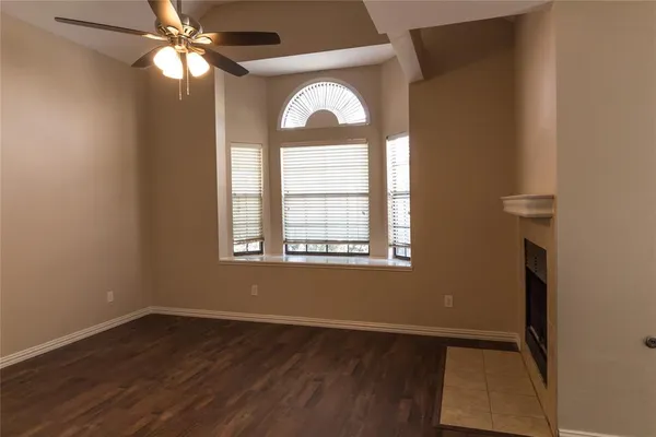 a view of empty room with wooden floor fan and window