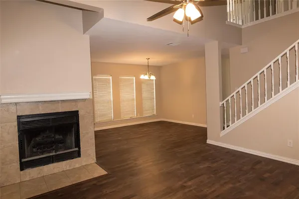 a view of an empty room with wooden floor fireplace and a window