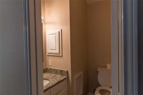a bathroom with a granite countertop toilet and a sink