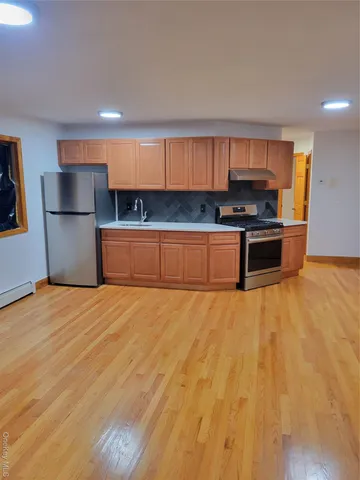 a kitchen with stainless steel appliances wooden floor and a refrigerator