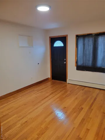 a view of an empty room with wooden floor and cabinet