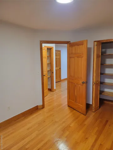 a view of an empty room with wooden floor and closet