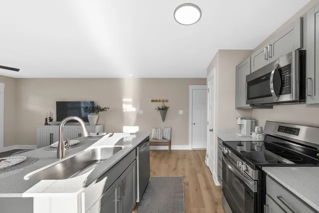 a kitchen with granite countertop a sink and a stove top oven with wooden floor