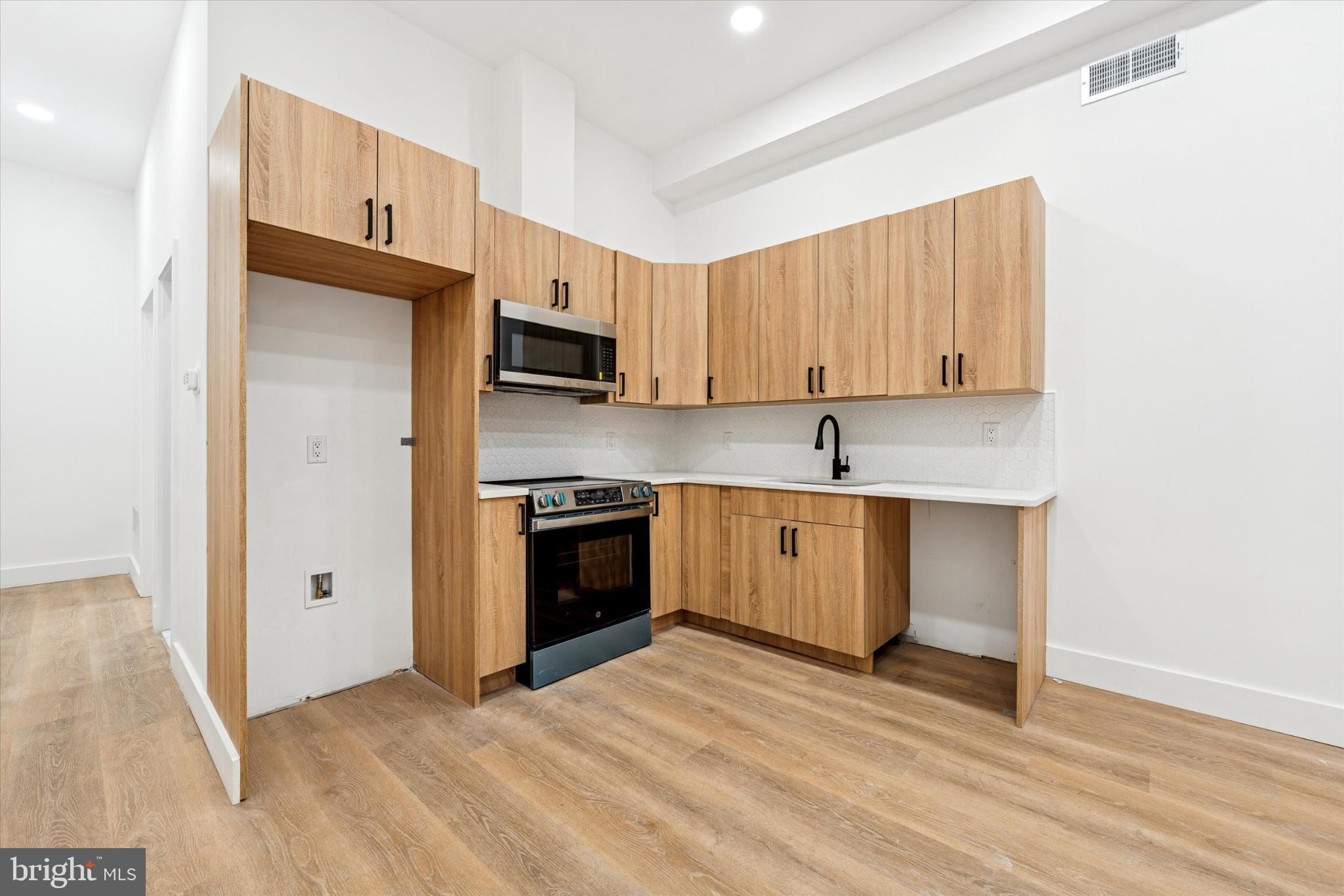 2424 West Thompson Street, Unit 3 Philadelphia, PA 19121 - Photo 4 of 14 a kitchen with stainless steel appliances granite countertop a stove a sink and a refrigerator